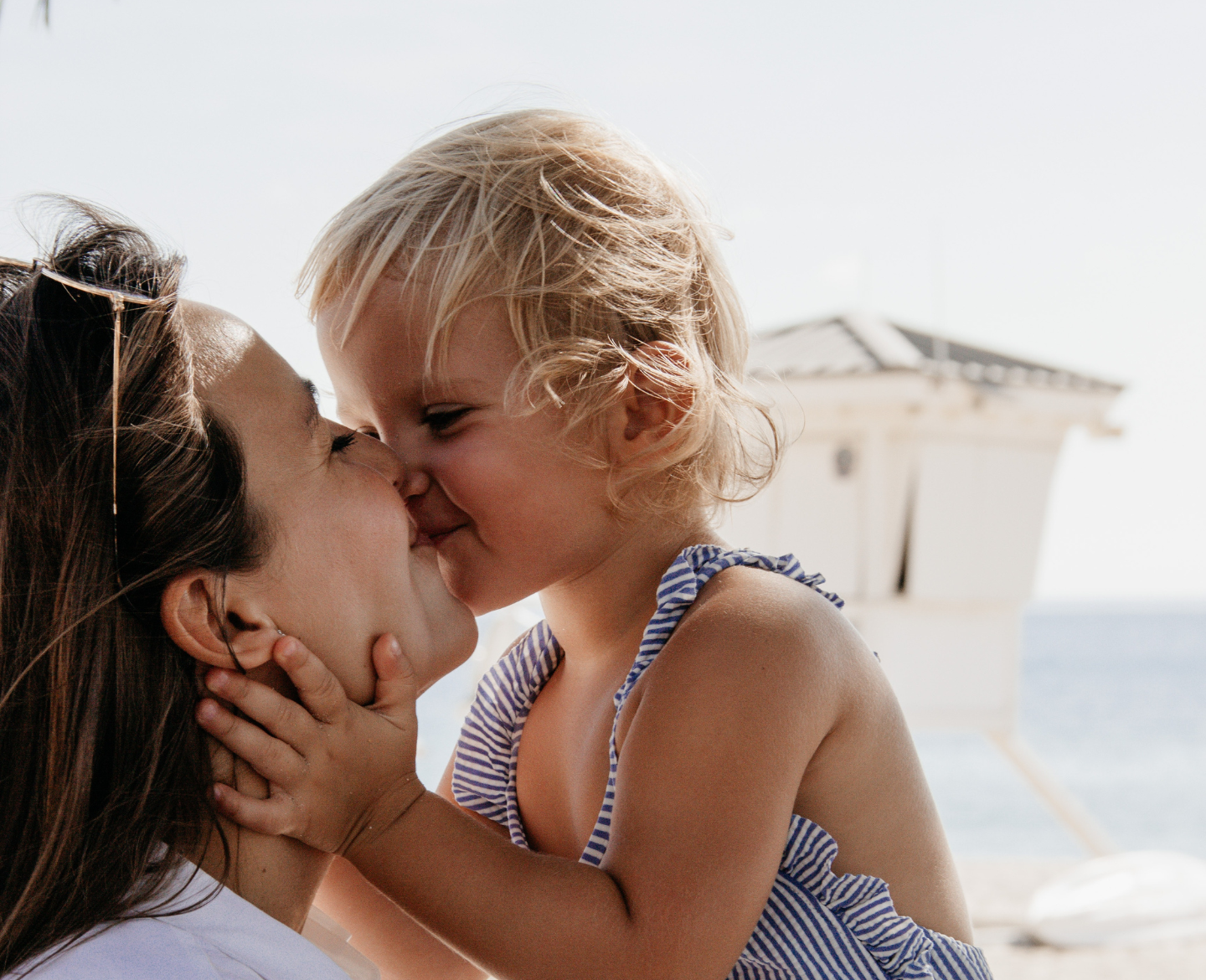 daughter kissing mom on beach