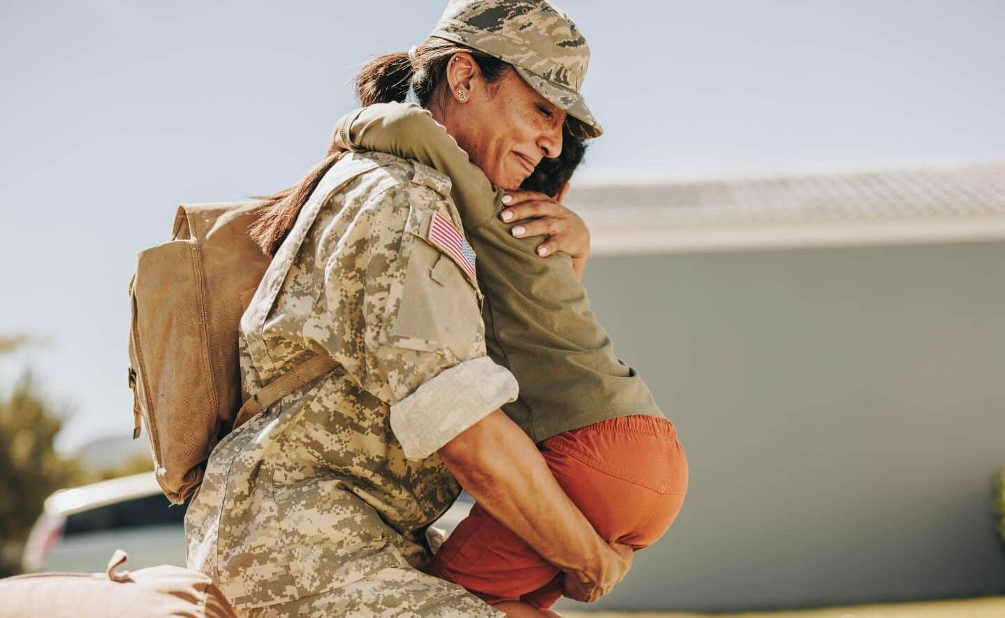 woman in military uniform hugging child