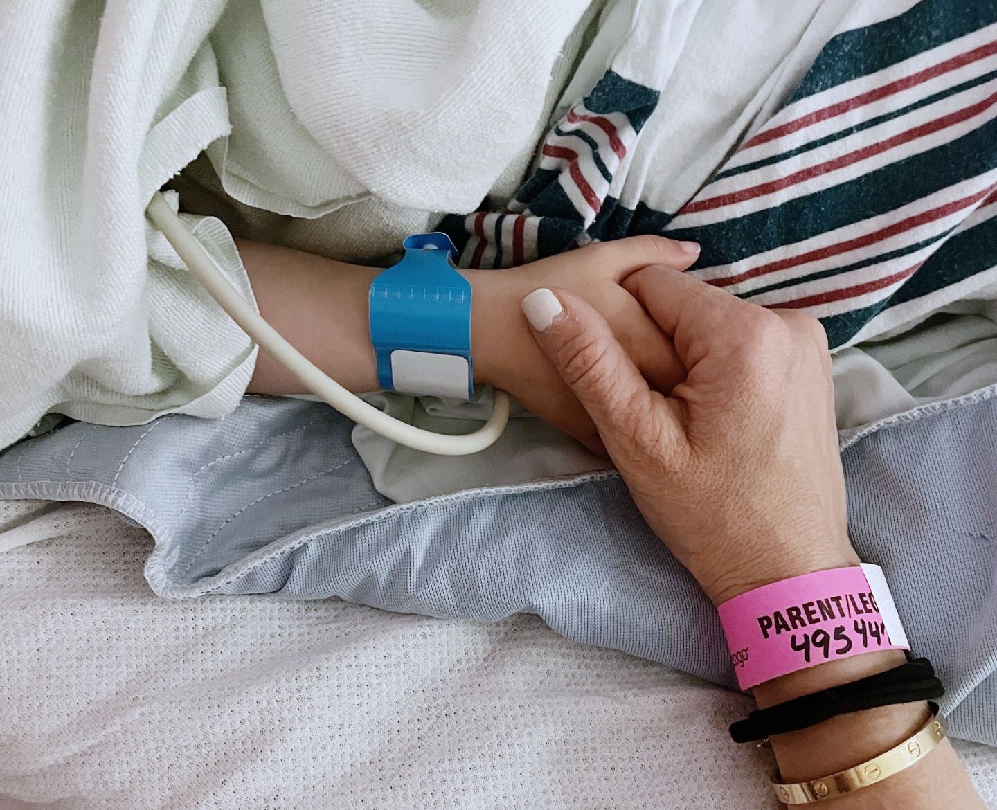 mom holding daughters hand in the hospital- childhood cancer