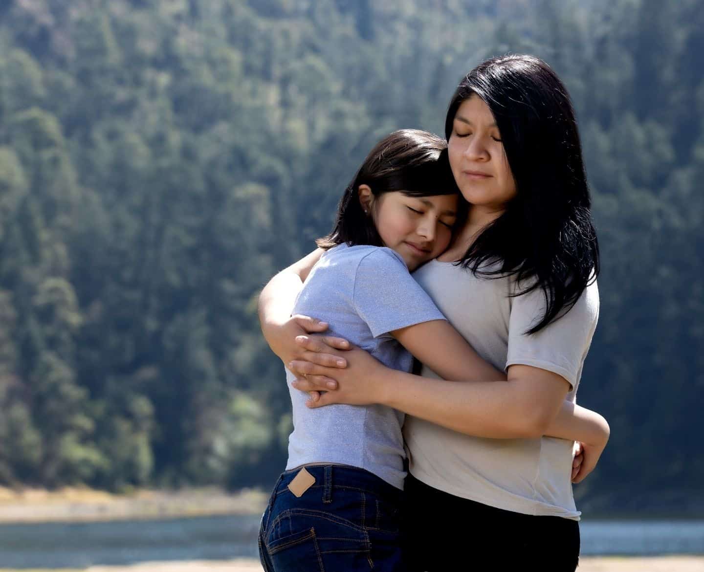 mother hugging teen daughter outside