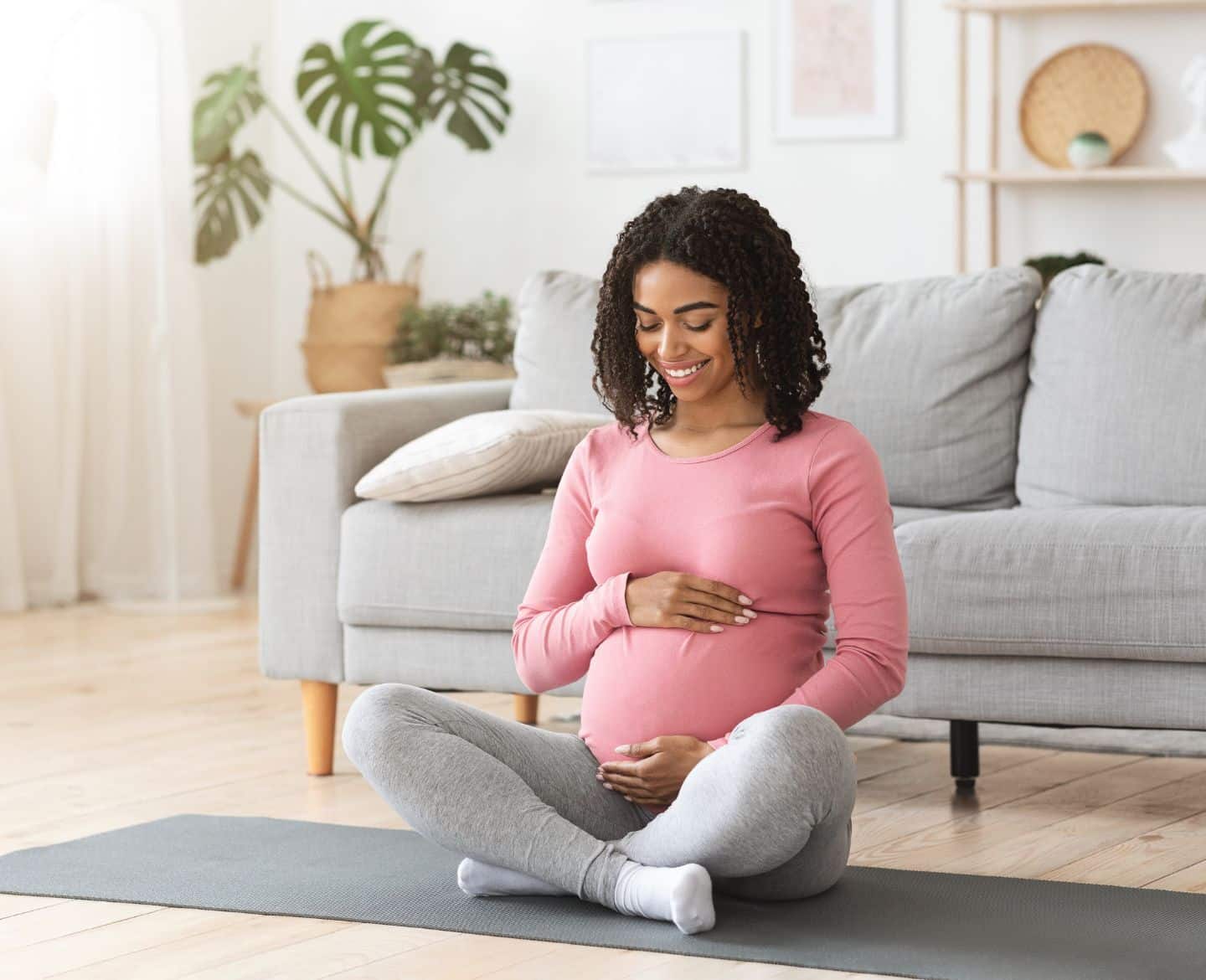 pregnant woman sitting on living room floor on a mat