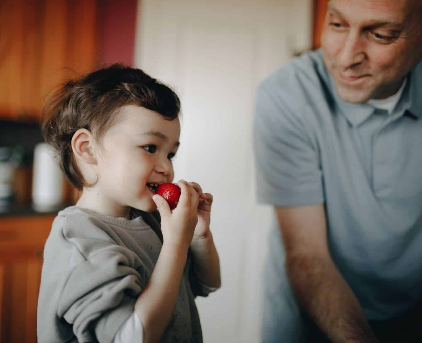 toddler eating strawberry at home with father - healthy food for picky eaters