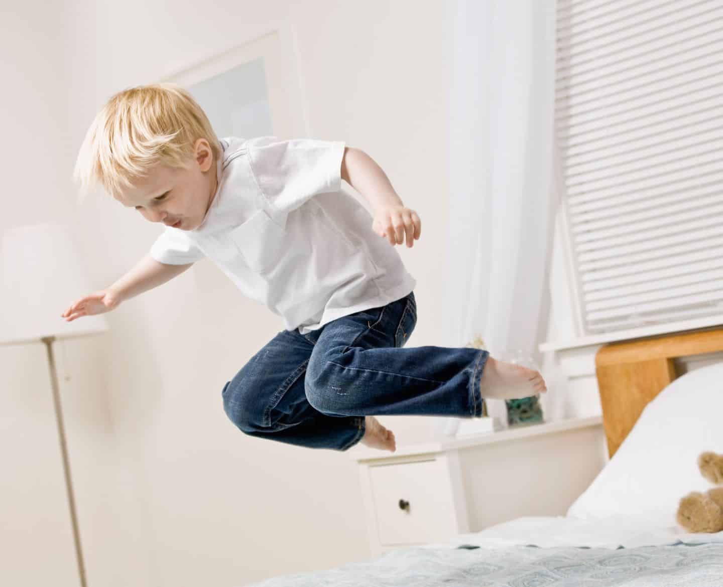 wild child boy jumping on bed