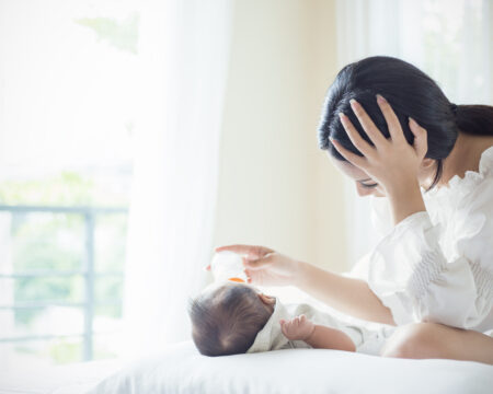 woman feeding baby on bed