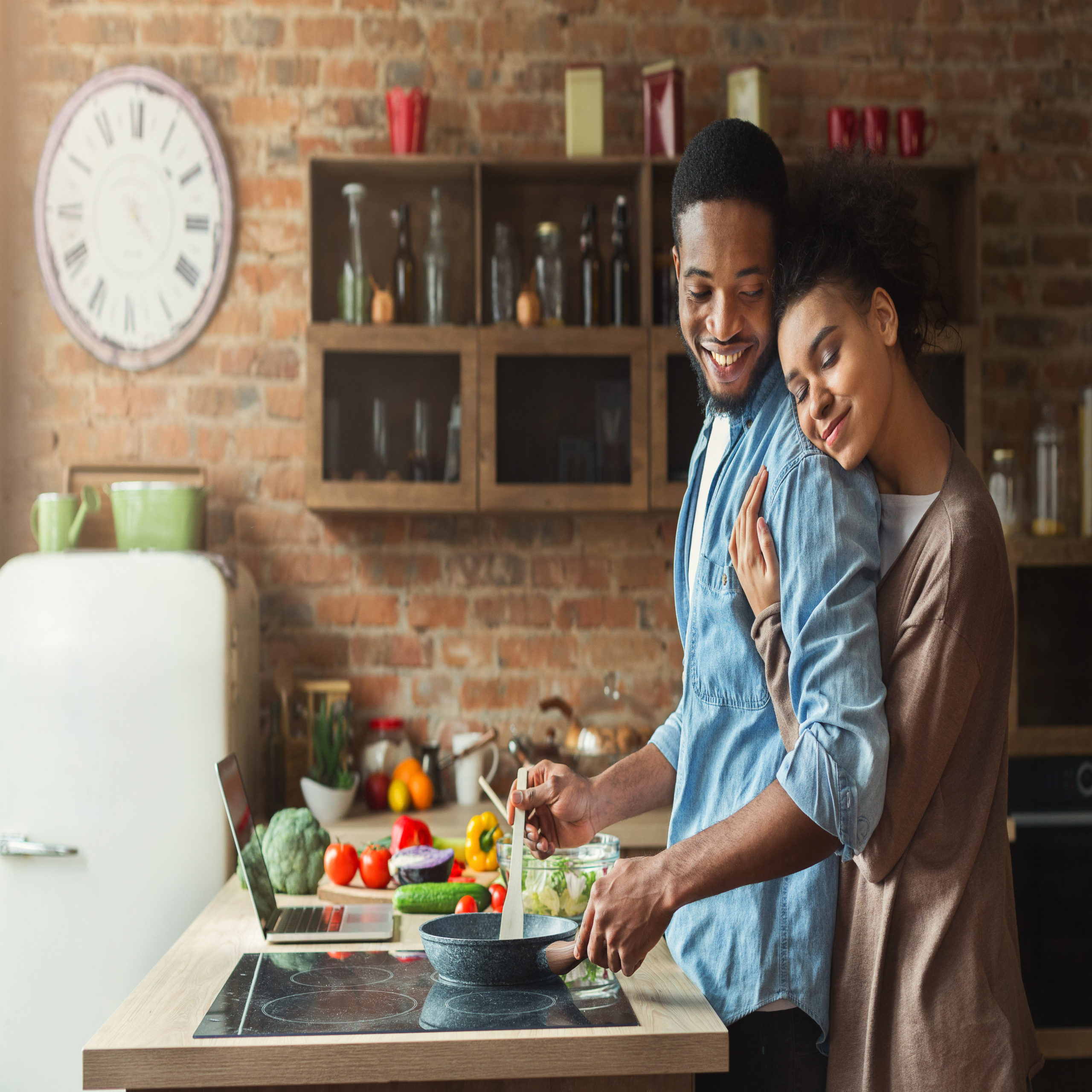 woman hugging partner while cooking dinner