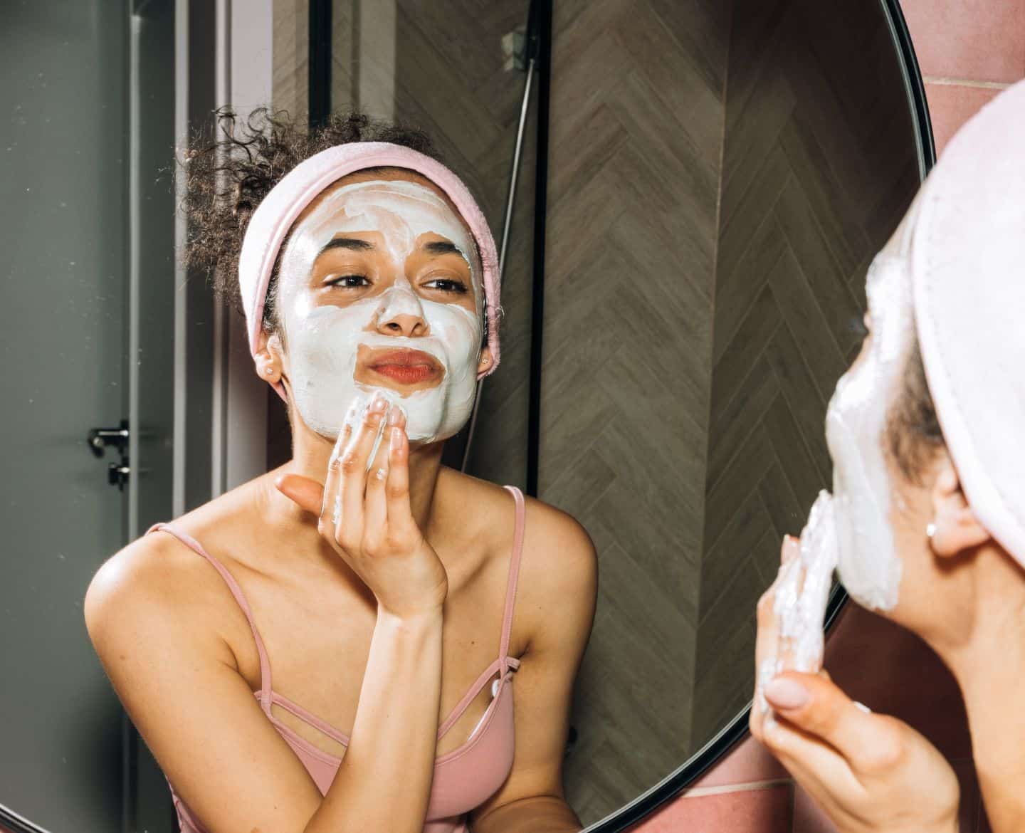 woman putting on a face mask in a mirror