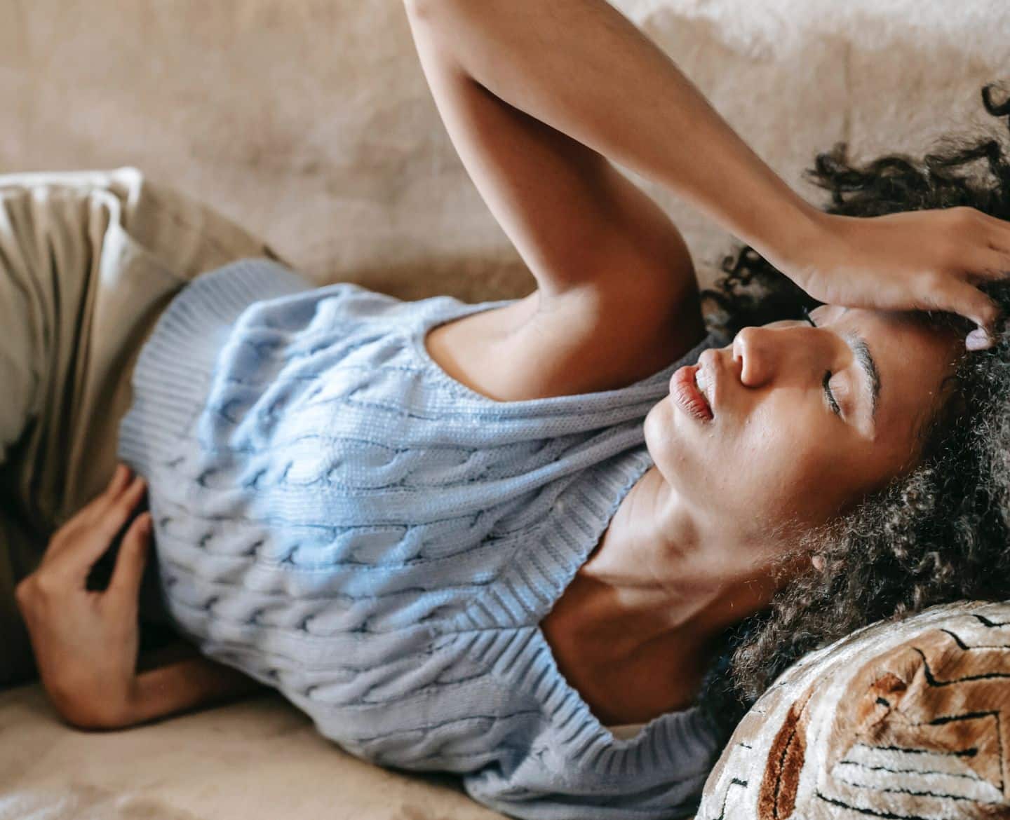 woman in pain laying on couch - period symptoms