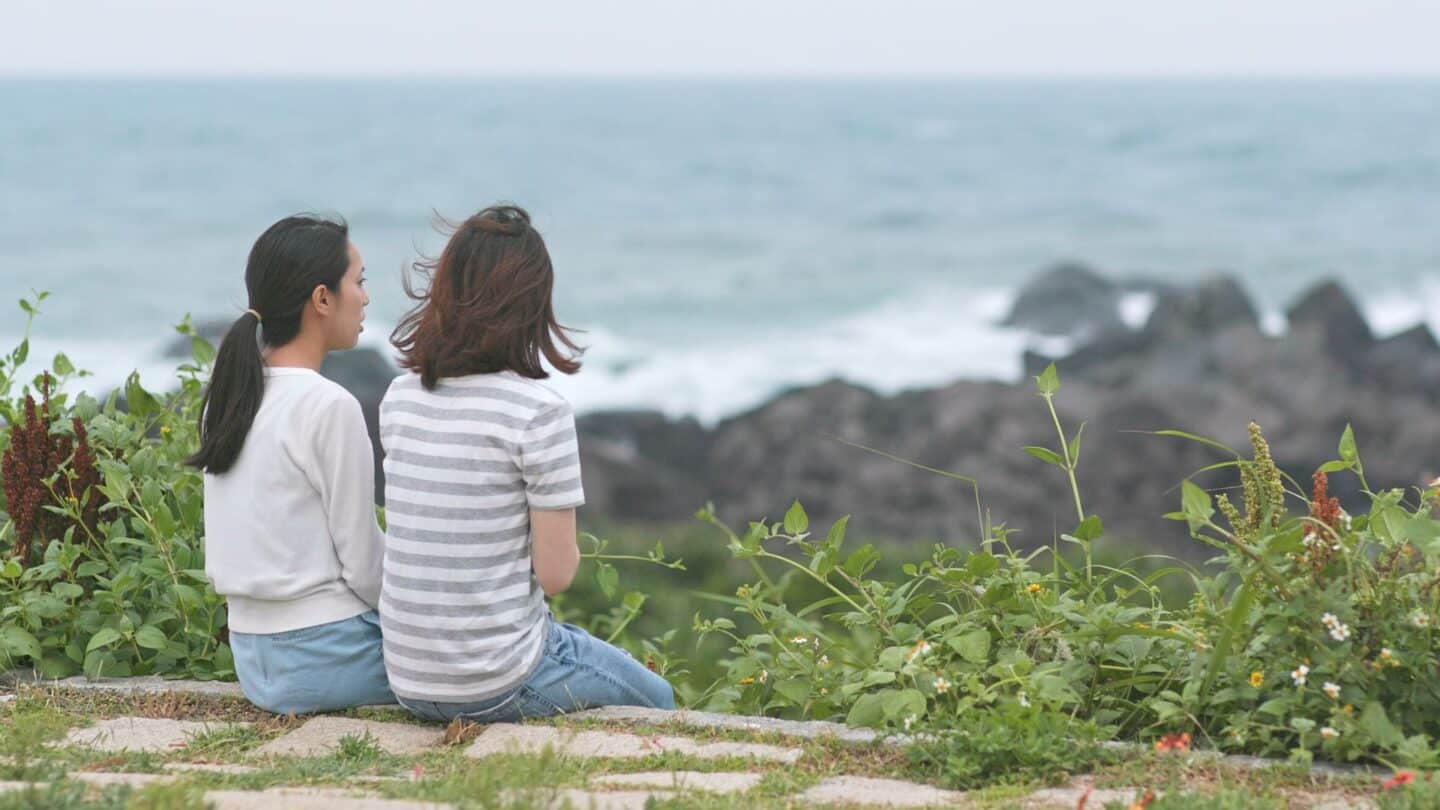 Two women talking looking out at rocky beach, discussing anxiety after miscarriage