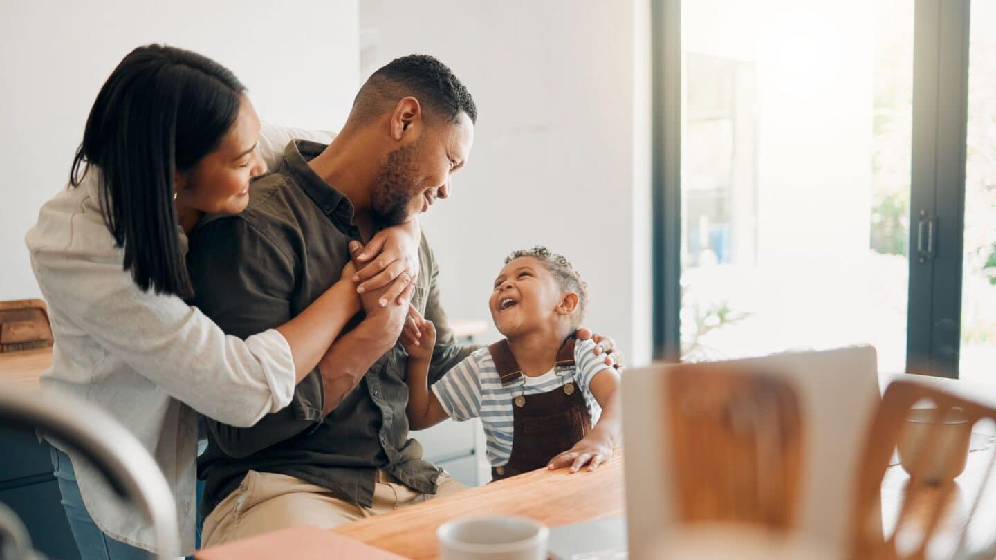 affectionate parents hugging in front of toddler son