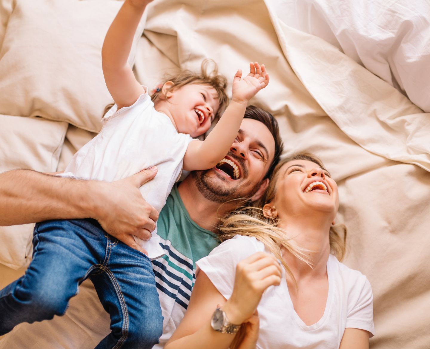 family laughing on bed - happy kids