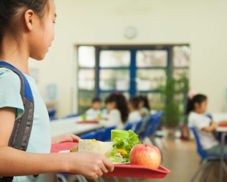 girl carrying school lunch tray free school lunch Motherly