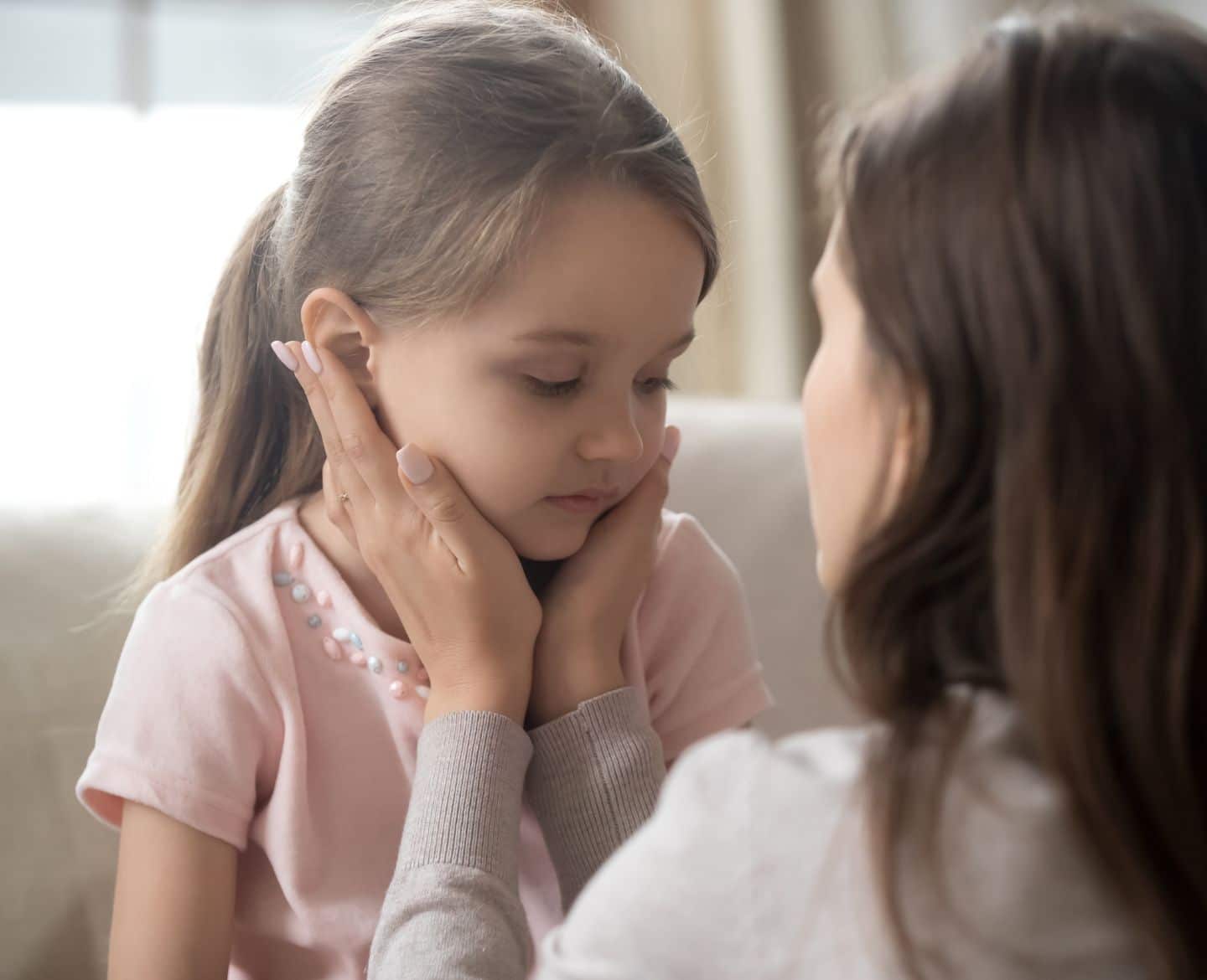 mom holding daughters face in hands to discuss friend betrayal