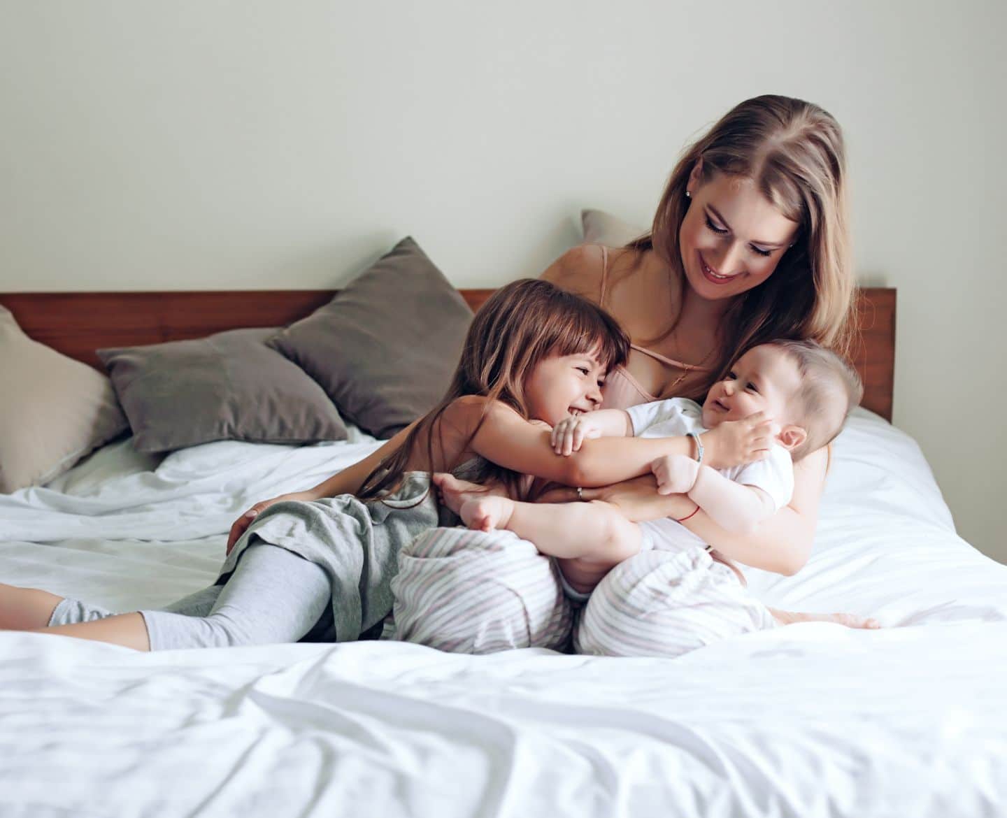 mom of two with second child baby and toddler in bed