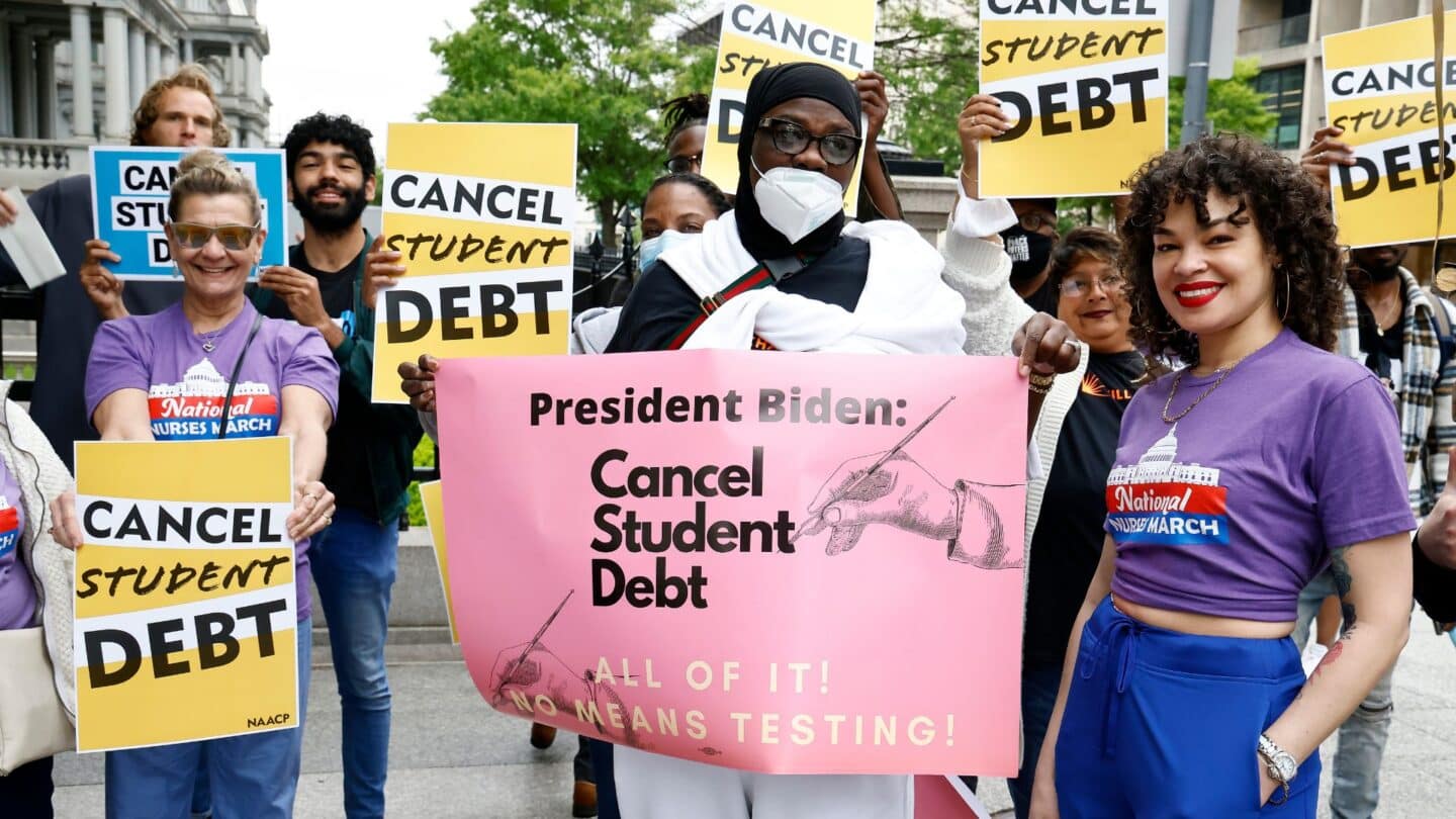 people holding signs about canceling student debt at a protest