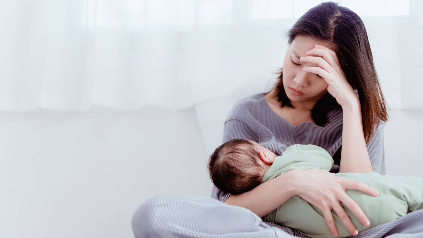 stressed out mom breastfeeding with her head in her hand