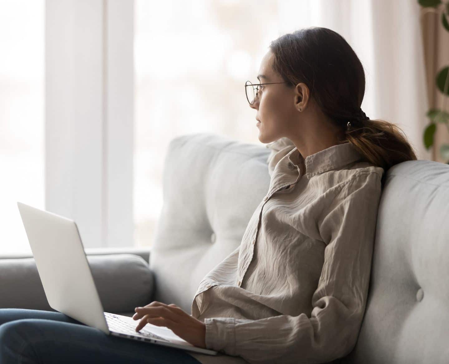 woman sitting on couch holding laptop - quiet quitting