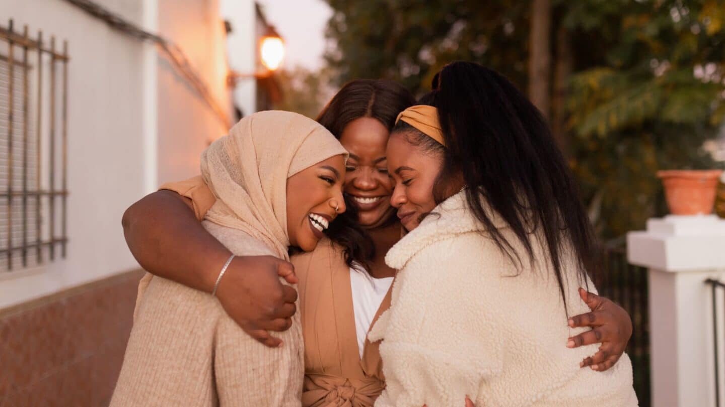 group of three women hugging - tear each other down