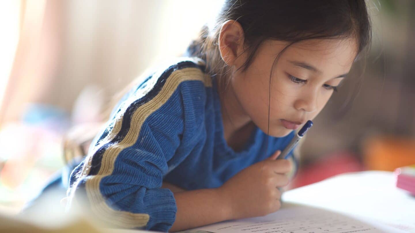 young child leaning over book, doing homework assignments