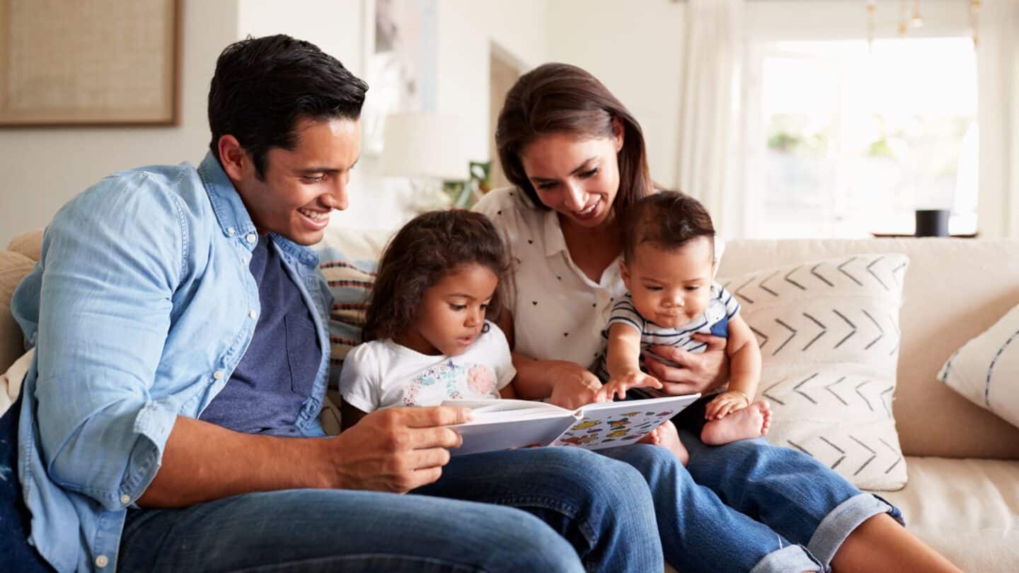 young Hispanic family sitting on couch reading a book - second generation hispanic