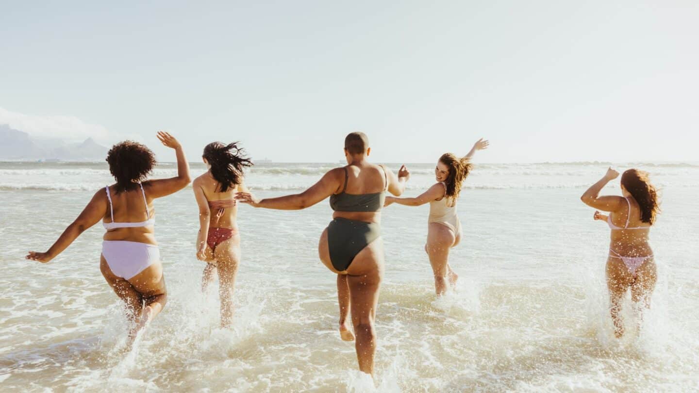 cheerful women in bathing suits at the beach showing real women bodies