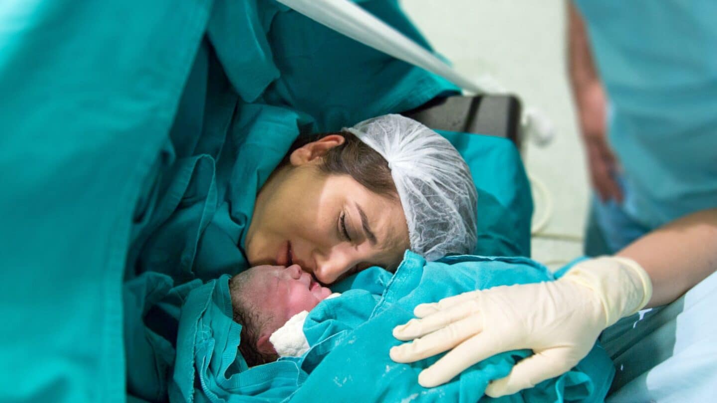 mother embracing newborn baby after c-section, representing the latest step in the history of the c-section