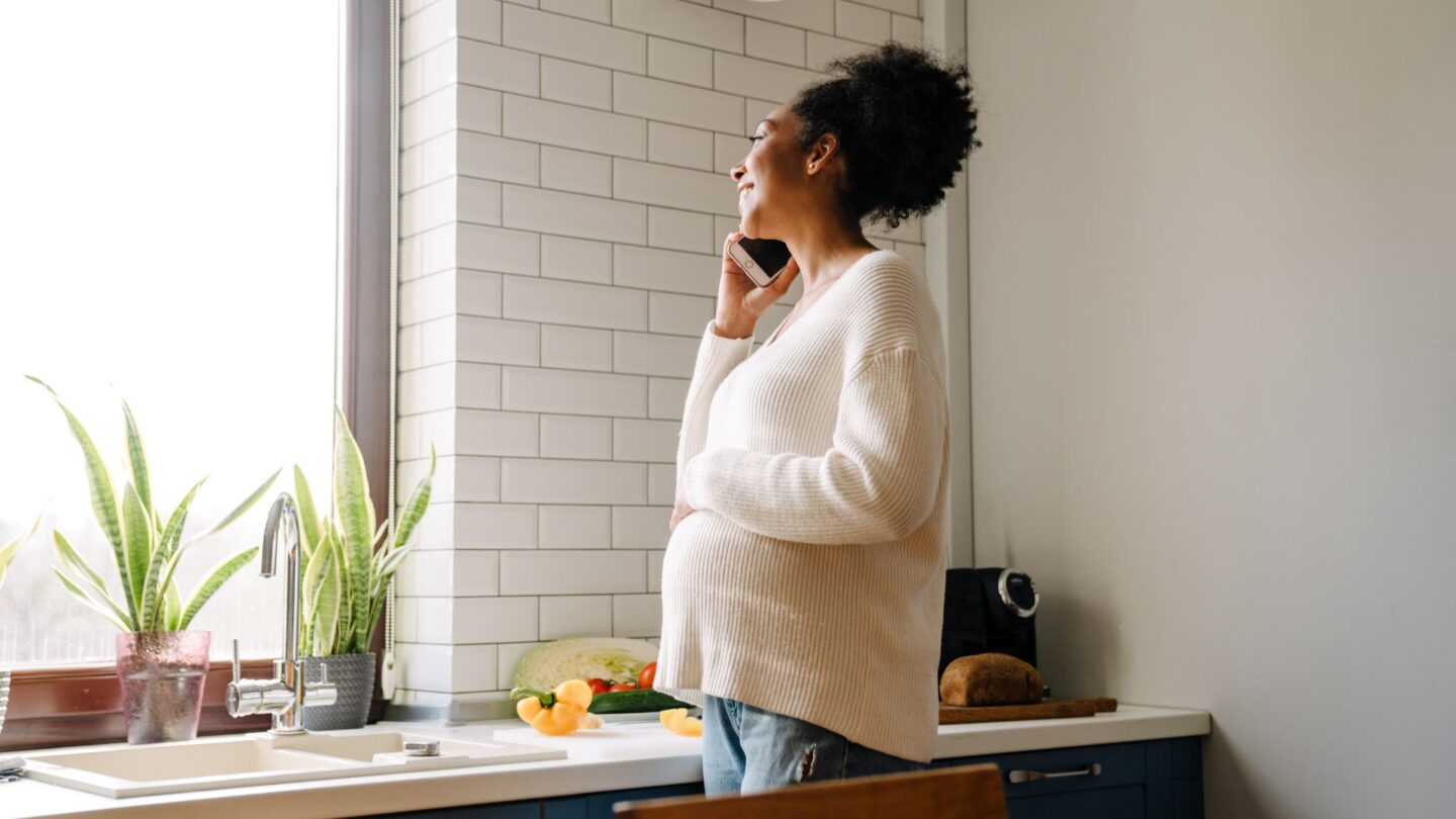 pregnant woman in kitchen talking on phone about pcos and pregnancy