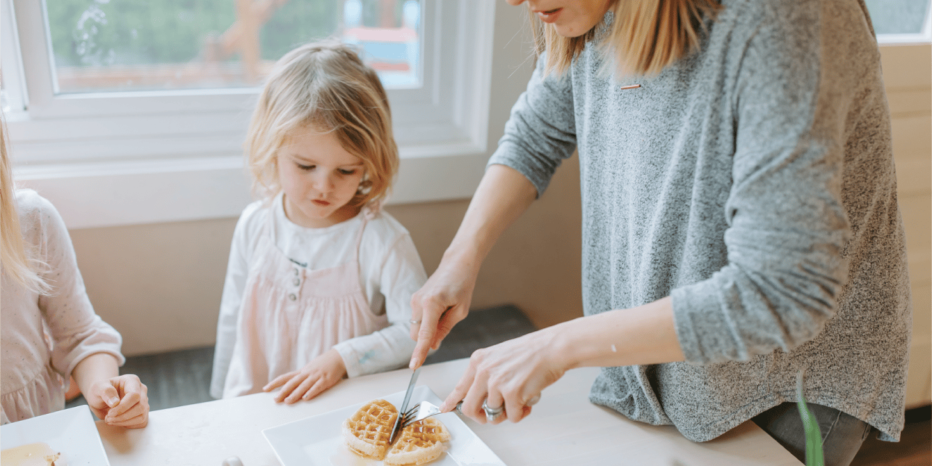 mom cutting a little girls waffle - picky eating tips