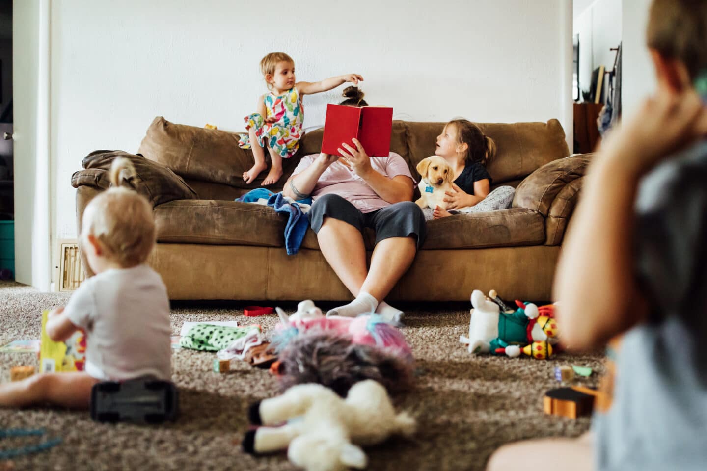 mom reading a book with kids surrounding her - essay on mom brain is real