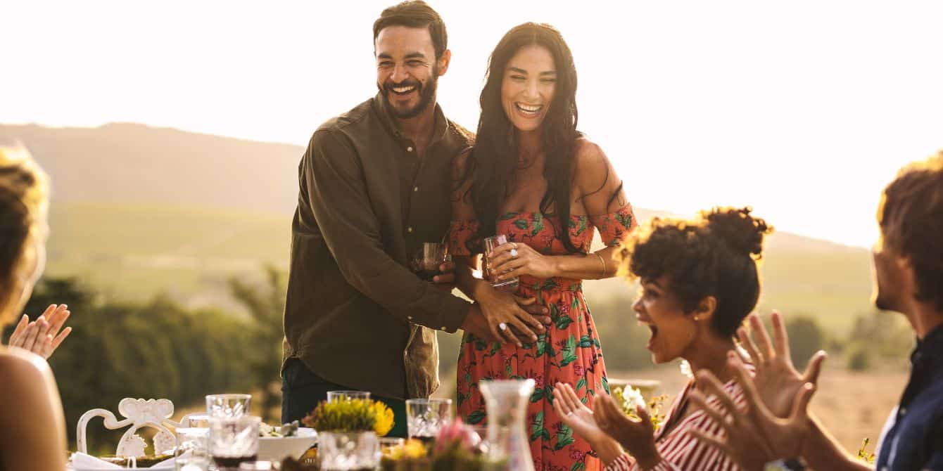 couple sharing pregnancy announcement with friends at dinner table- thanksgiving pregnancy announcement