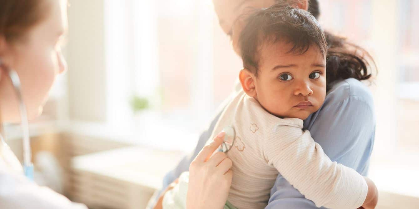 doctor listening to baby's lungs with stethoscope when talking with mother about rsv shot