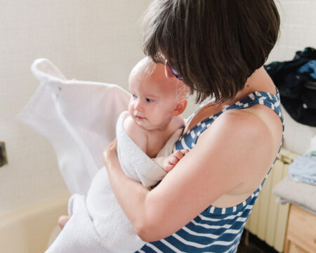 mom holding baby wrapped in a towel - how to give a baby a bath