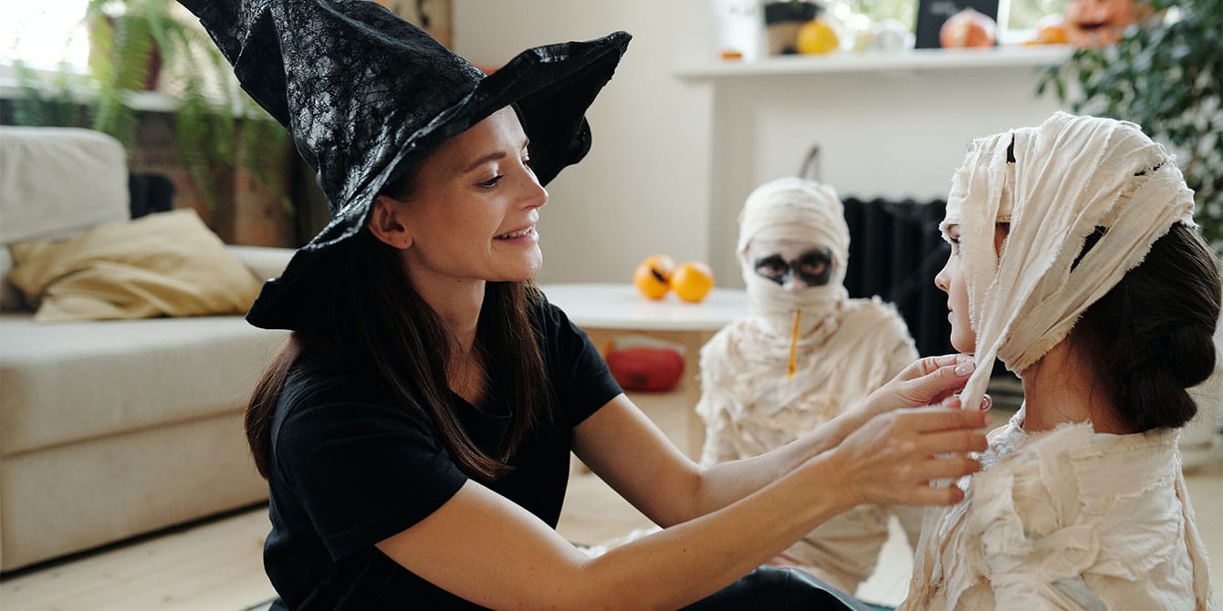 mom helping her kid put on mummy Halloween costume keeping Halloween safety in mind