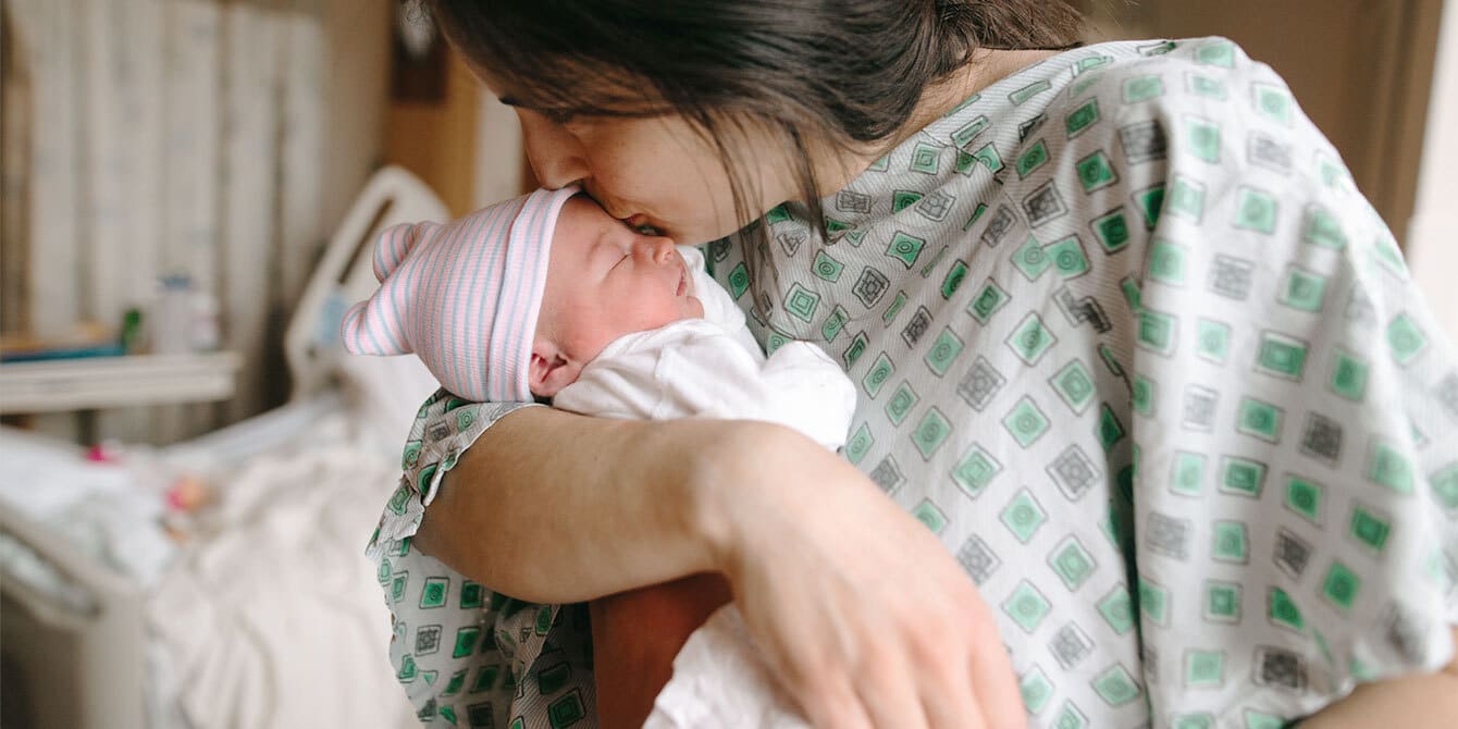 mother in hospital kissing premature baby shows what it's like having a premature baby