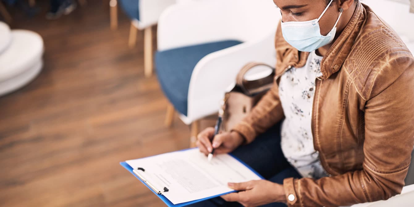 woman filling out paperwork at doctor's office after making one of her doctor appointments for women