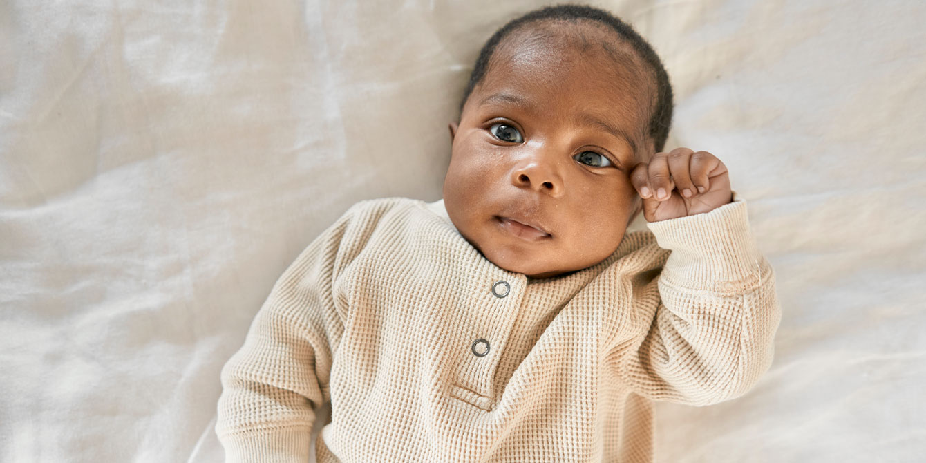 baby holding his hand up to his eye - should my baby get a newborn vitamin k shot and erythromycin eye ointment