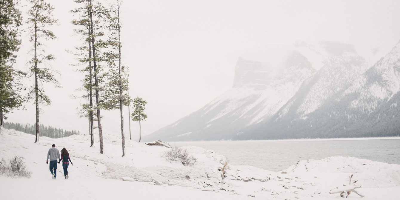 couple walking through the snow in the mountains -bucket list trips