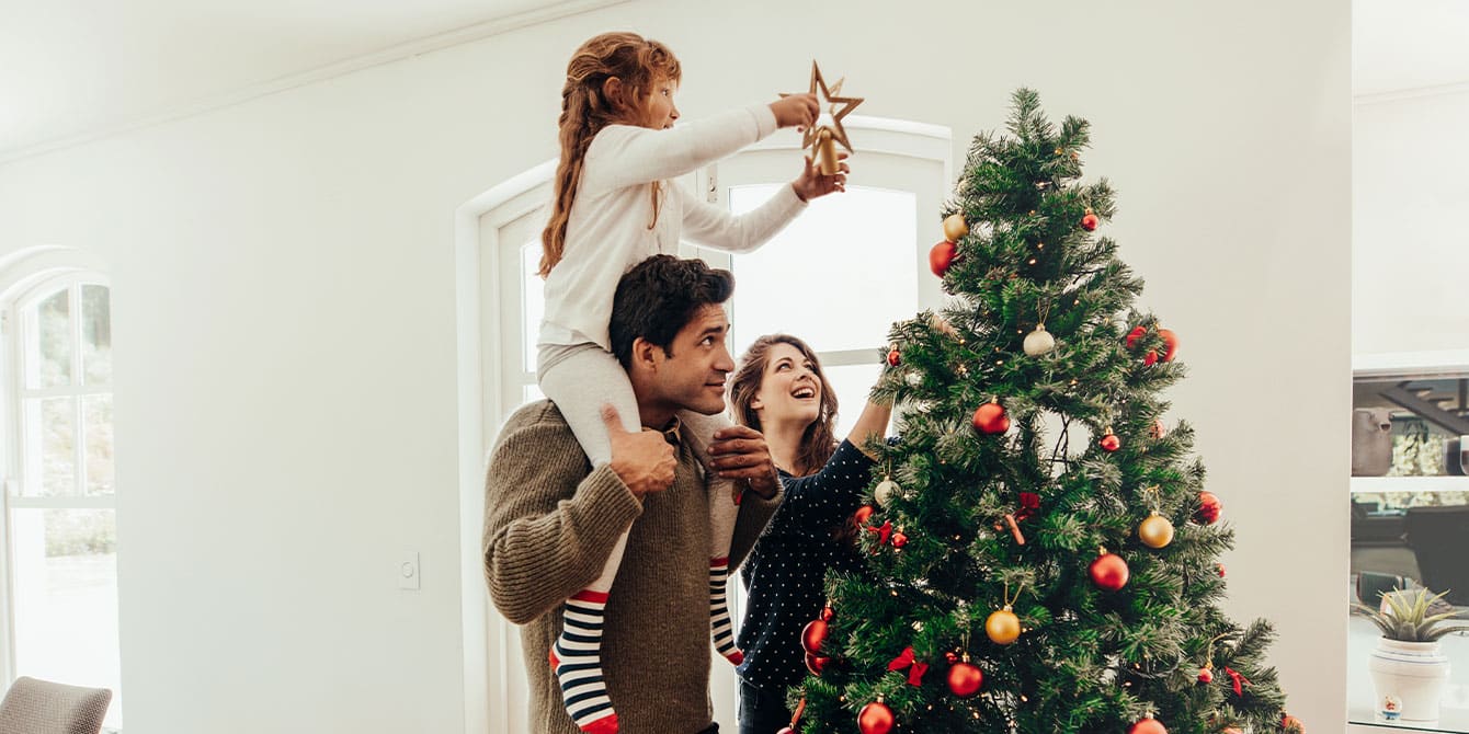 family celebrating christmas in november decorating a christmas tree