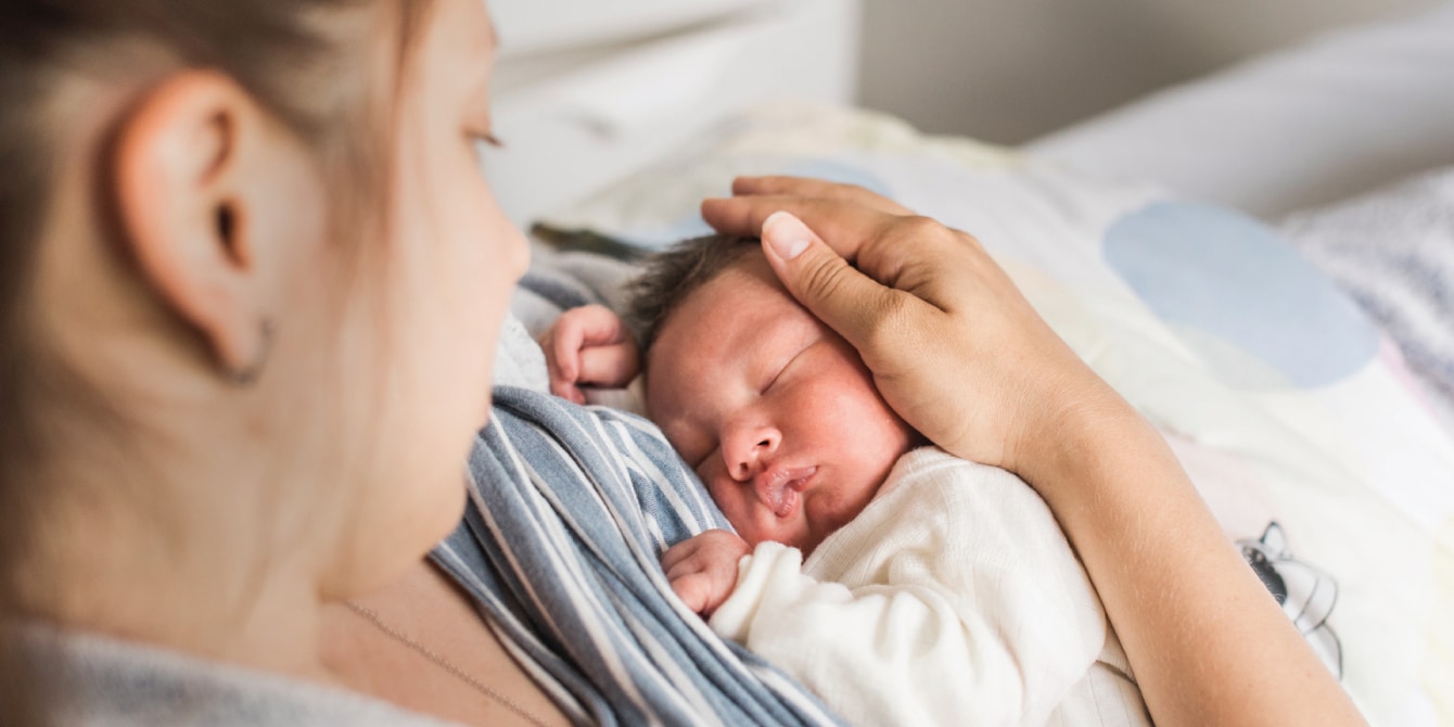 mom snuggling newborns head - postpartum confinement