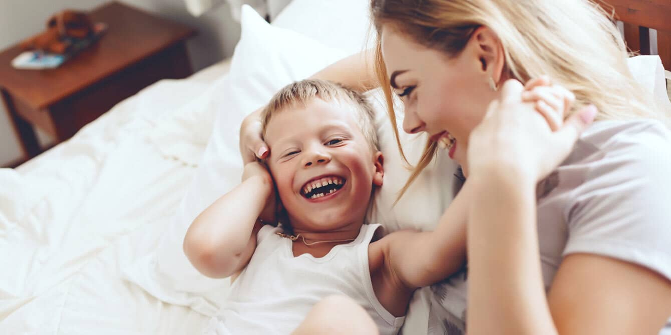 mom working on mental health making son laugh in bed