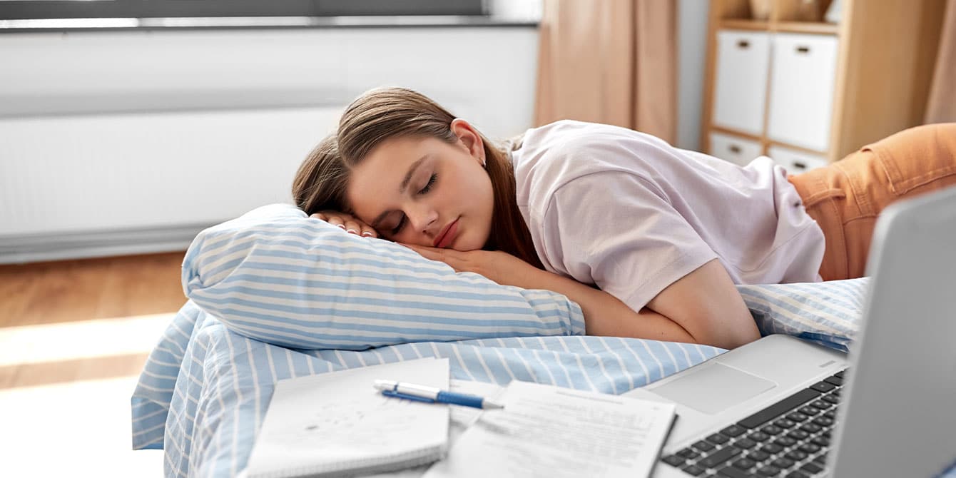 teenage girl taking a nap while doing homework - teens and sleep