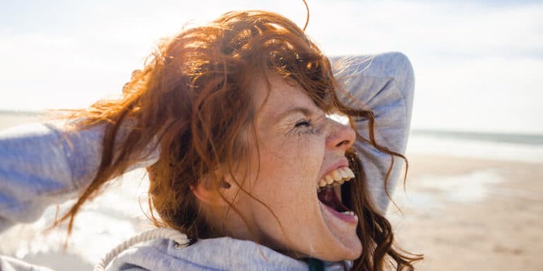 Woman at the beach screaming in scream therapy for self-care