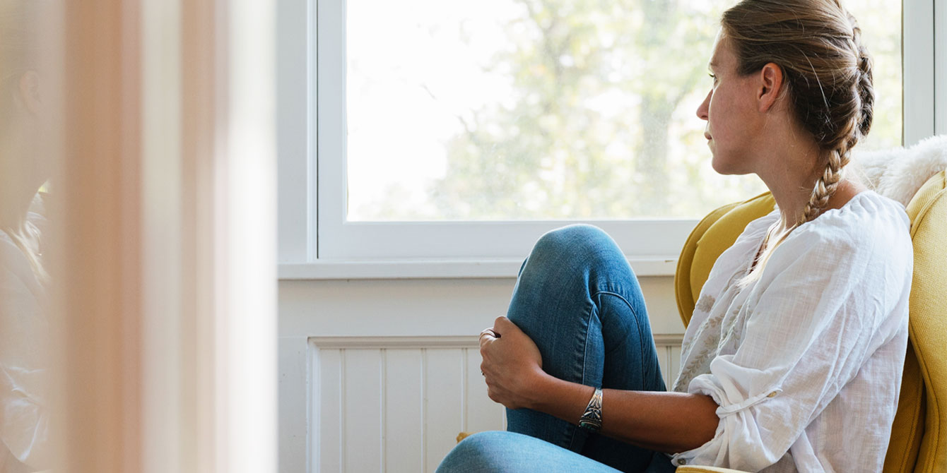 grief-stricken woman sitting and staring out of a window