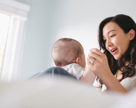 young mom playing with baby on the bed Motherly