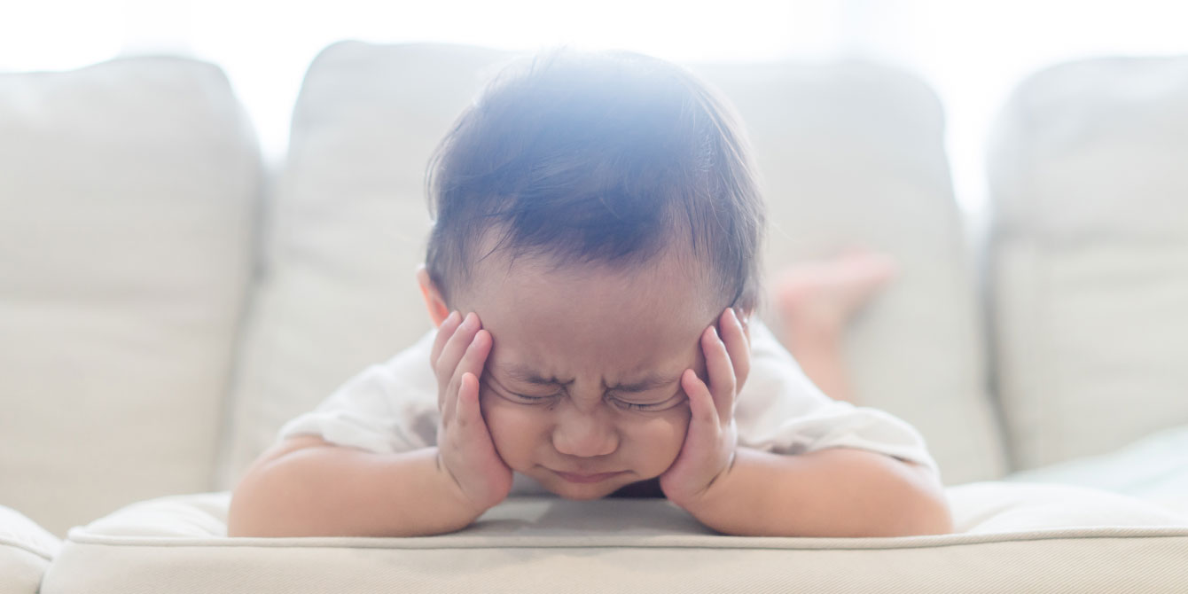 baby laying on couch making a grumpy face - toddler refuses to potty train