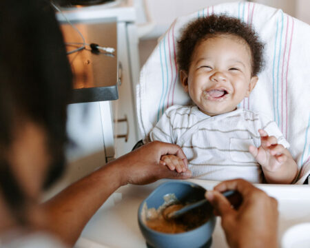 baby smiling while eating baby food
