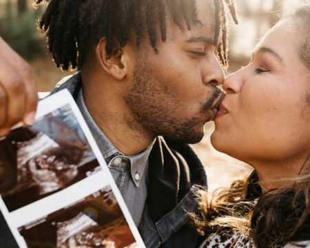 couple kissing while holding up an ultrasound Motherly