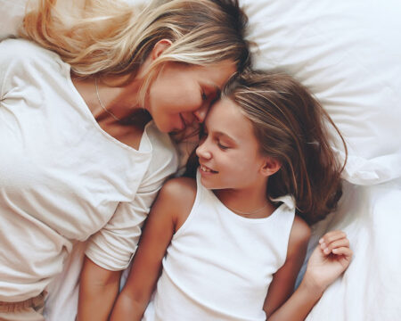 mom and daughter laying in bed laughing co sleeping with older kids