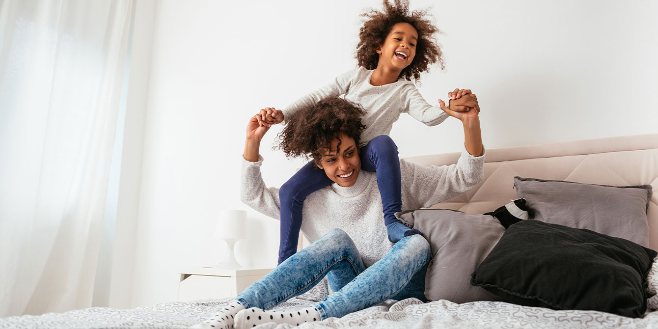 mom and son laughing on the bed playing not stressed about having a clean home