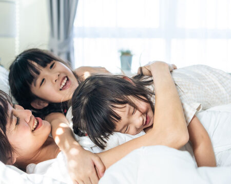 mom being a good enough parent hugging her two daughters in bed