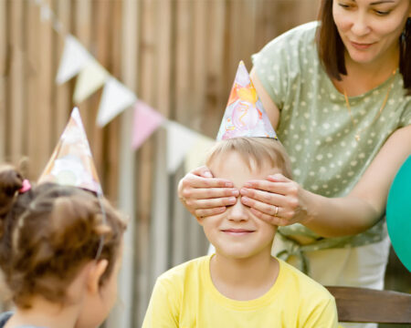 mom covering sons eyes for surprise childhood birthday parties